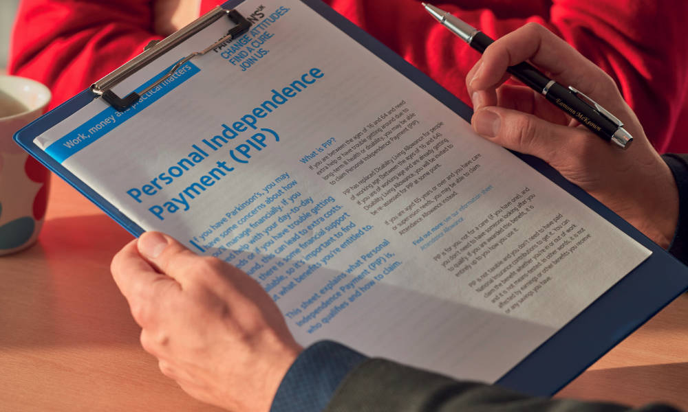 Person carefully filling out a PIP application form with support from an expert report.